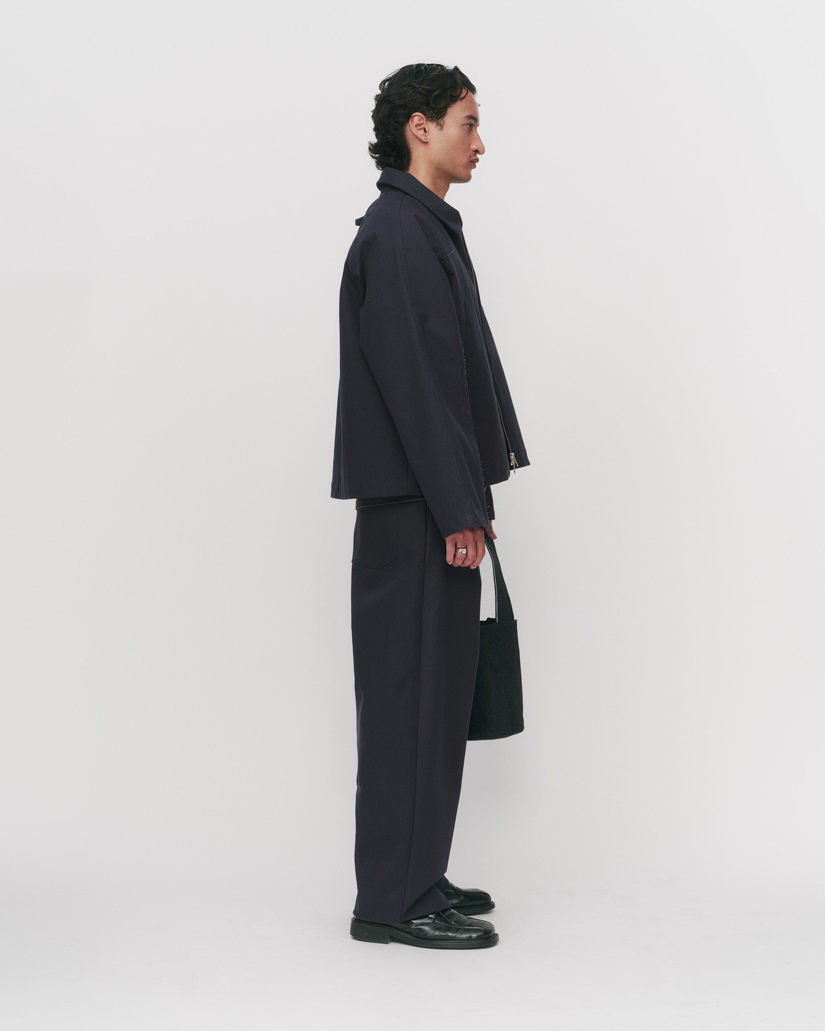 Person wearing a navy outfit standing against a white background