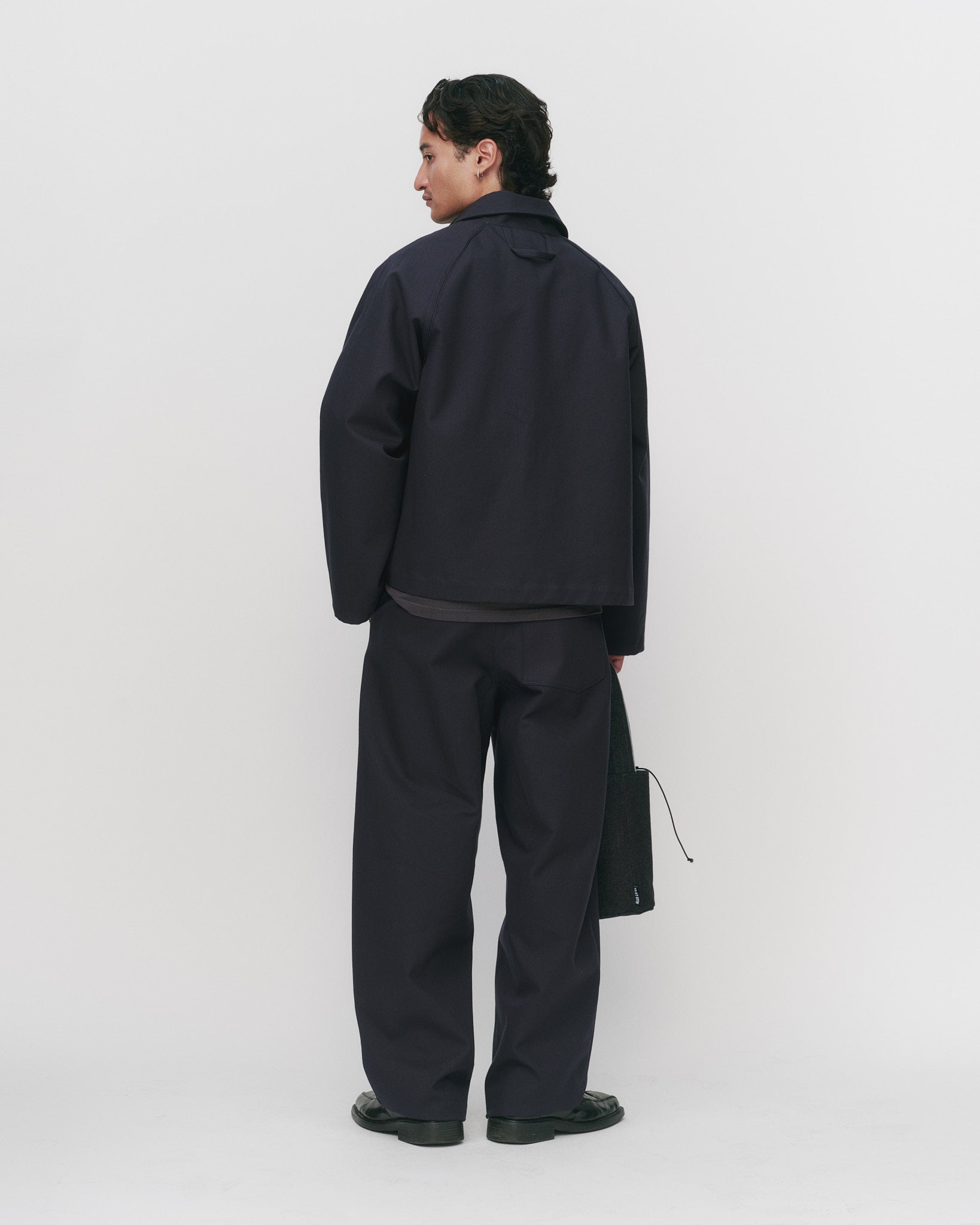 Person wearing an all navy outfit with a jacket and pants on a white background