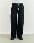 Dark japanese selvedge denim pants with exposed button details worn by a person against a white background