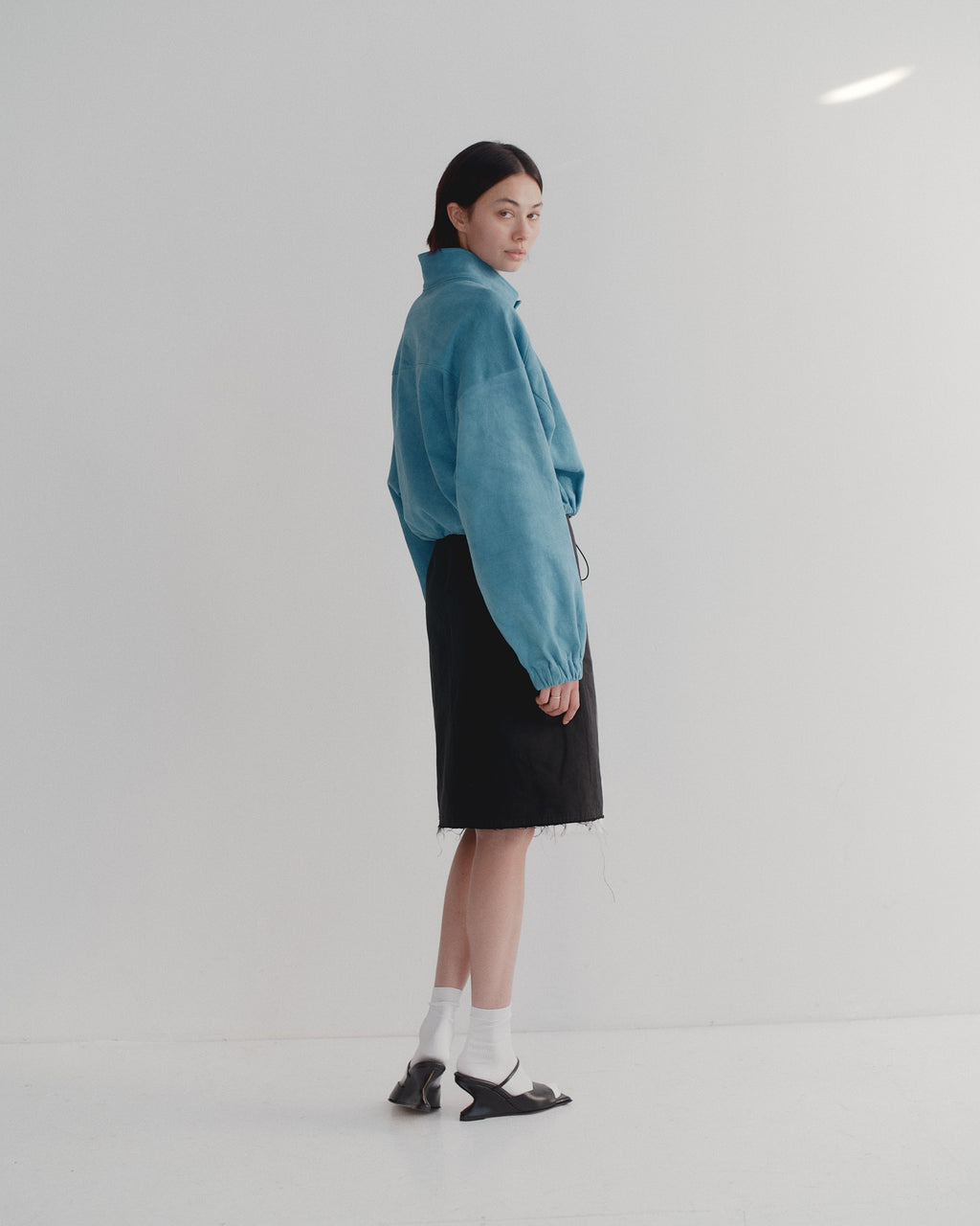 Person wearing a blue jacket and black skirt on a white background