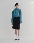 Person wearing a bright blue brushed cotton studio bomber and black skirt on a white background