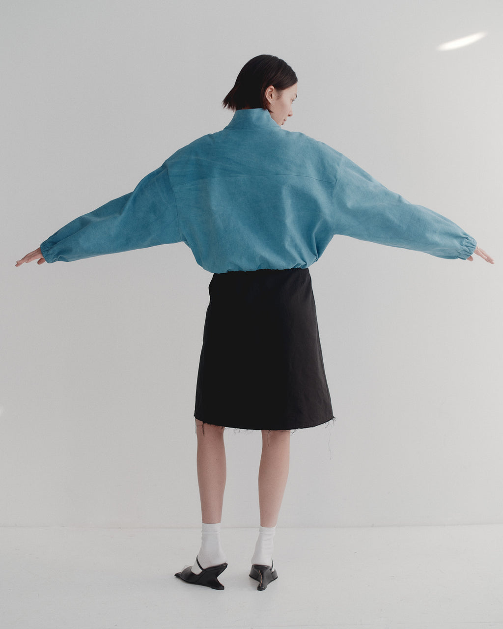 Model wearing a blue jacket and black skirt on a white background