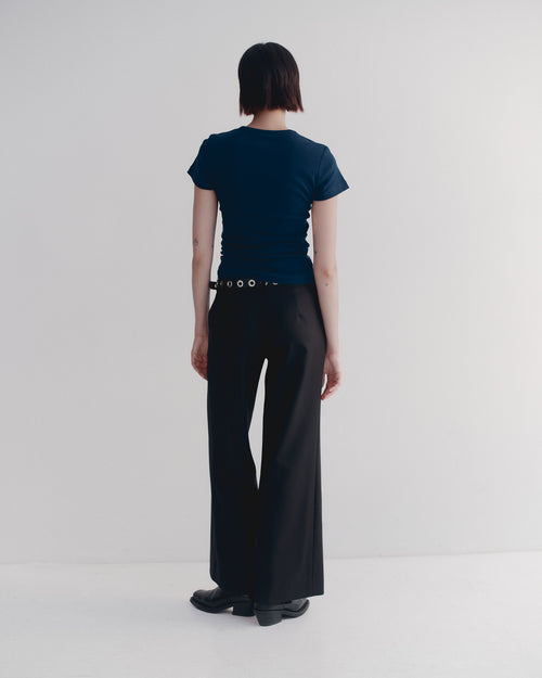 Person wearing a dark blue t-shirt and black pants against a white background